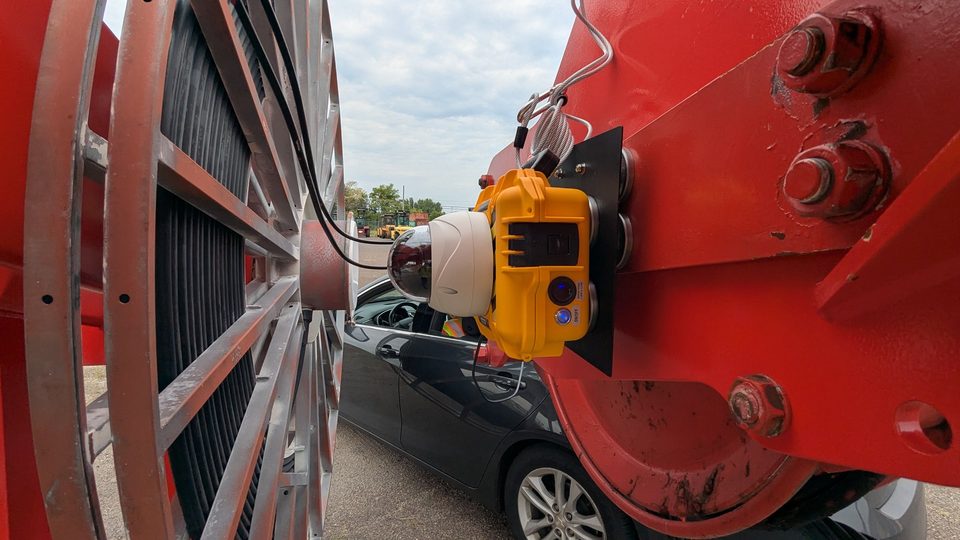HoistCam camera clamped to the red hook block of a mobile harbor crane at a marine terminal